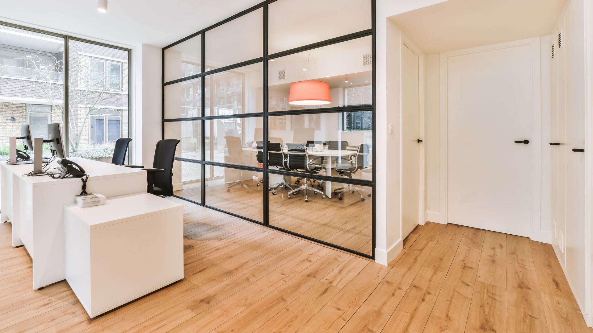 A room with a desk, chairs, and a large window